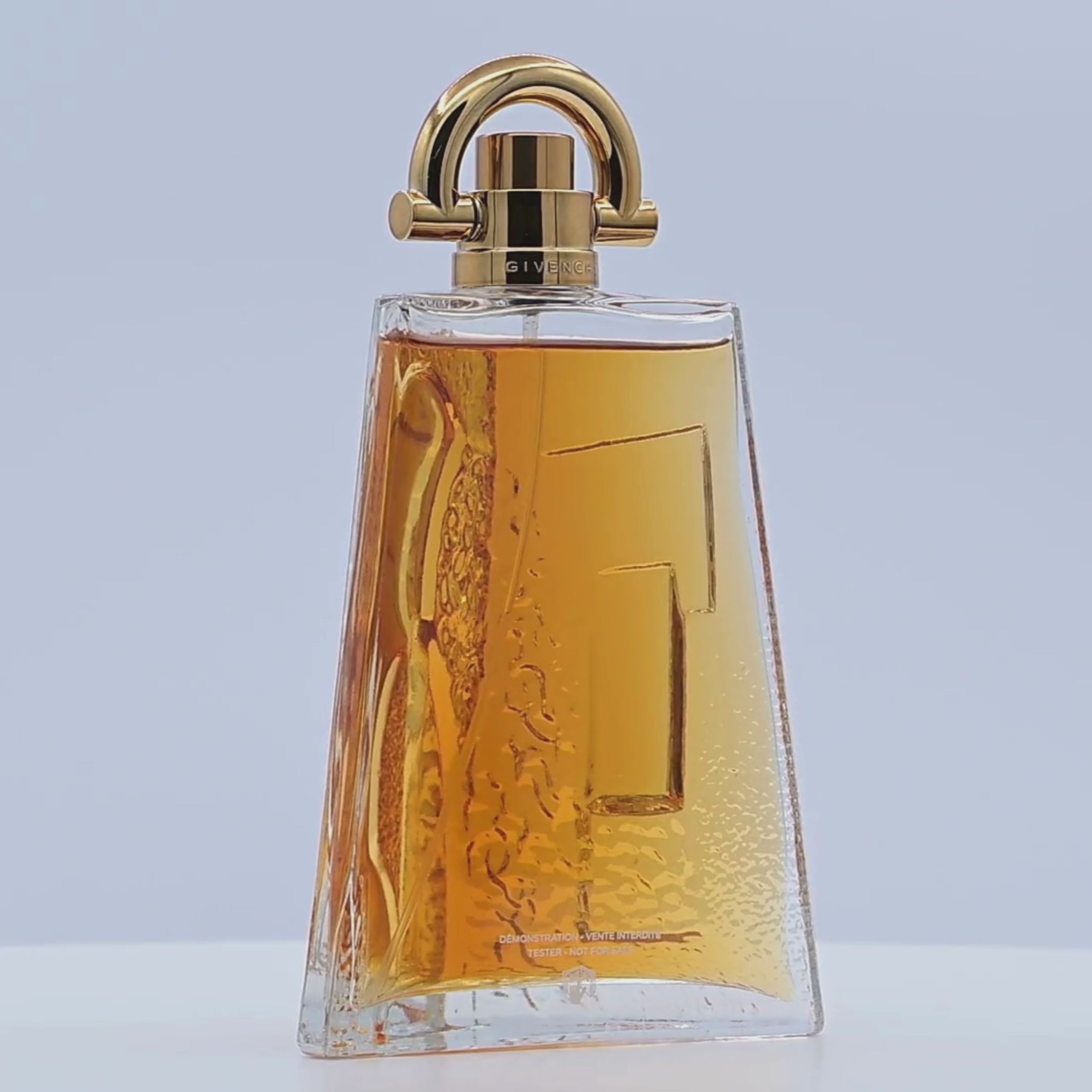 Perfume bottle with gold cap rotating on a white podium