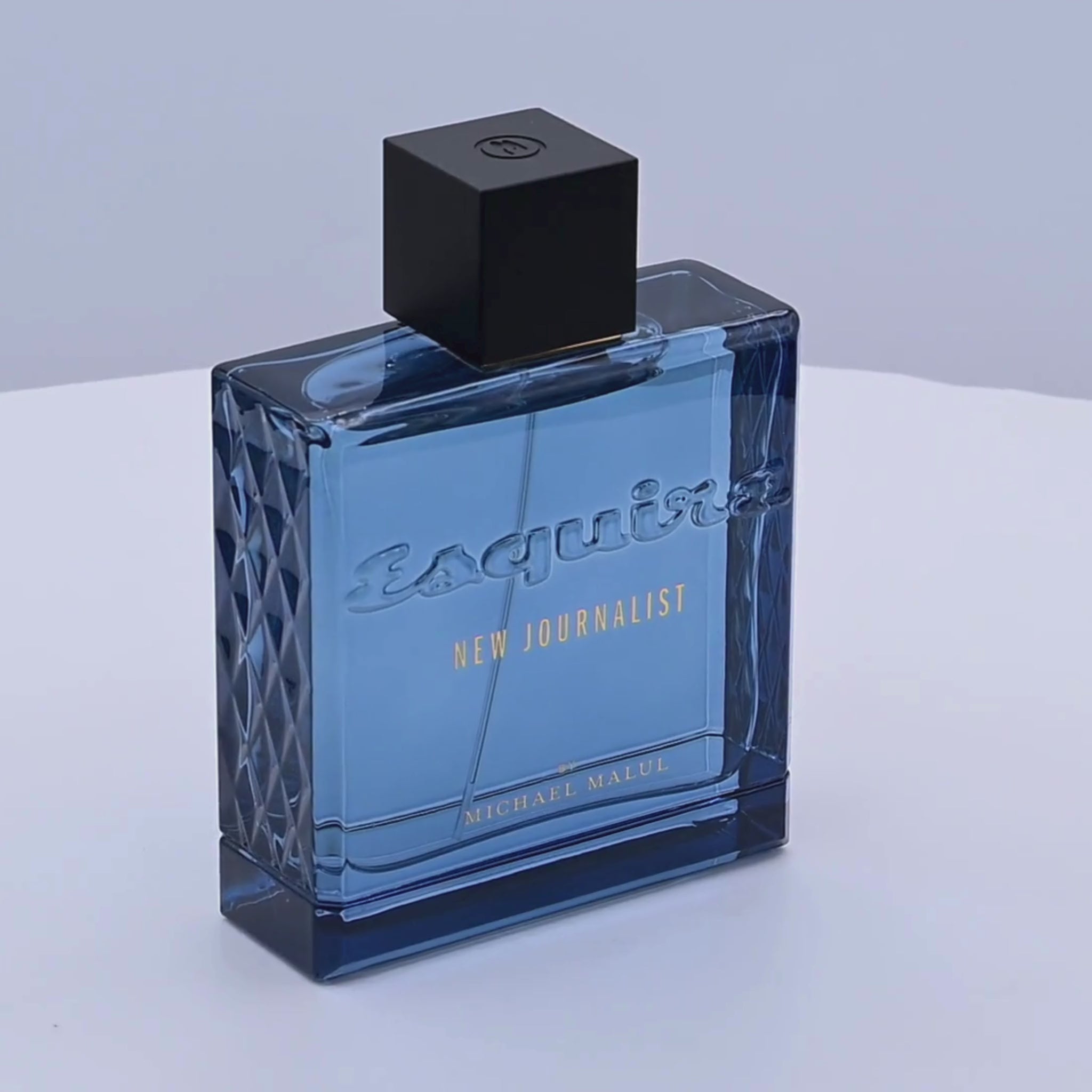Blue perfume bottle with black cap rotating on a white podium