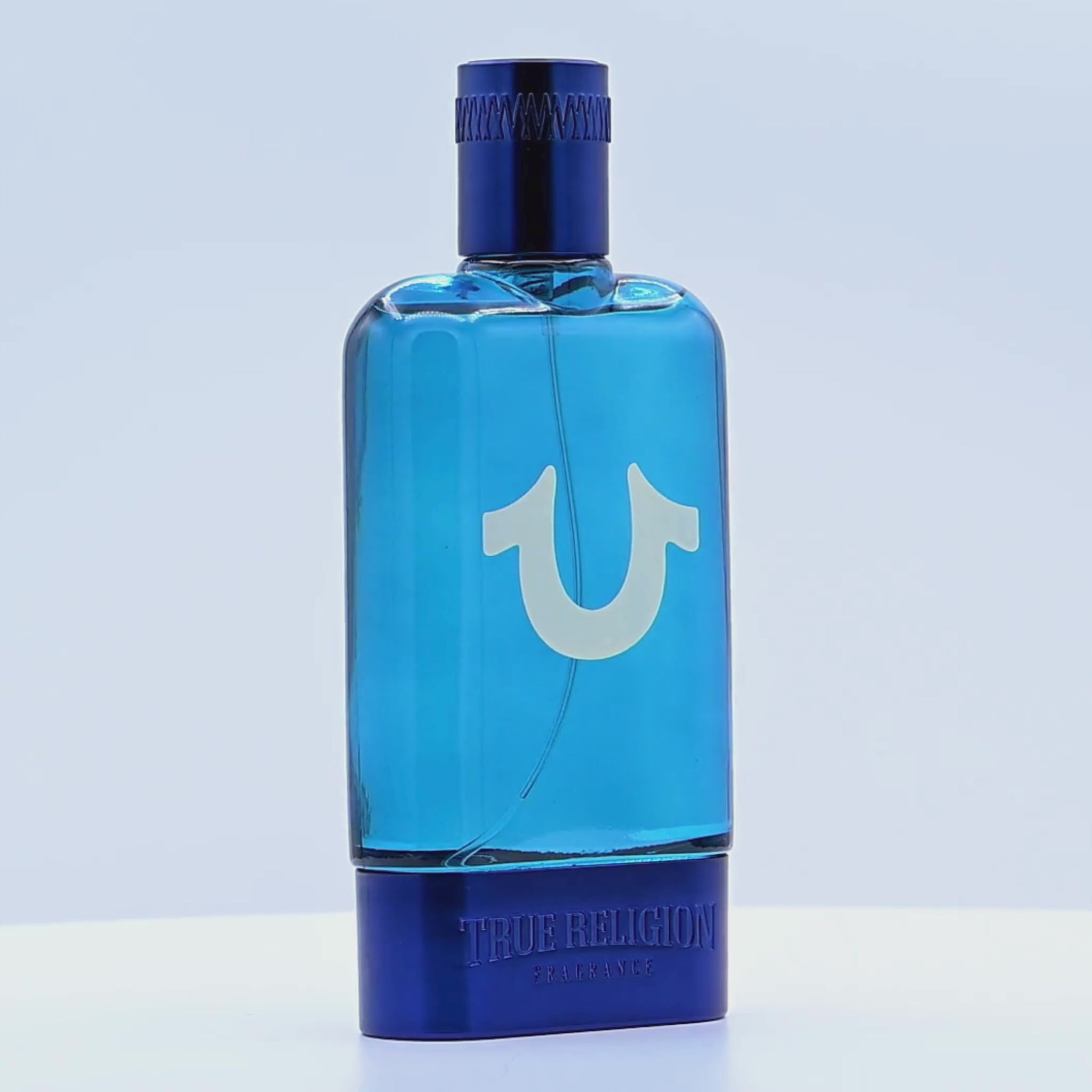 Blue perfume bottle with 'True Religion' branding rotating on a white podium