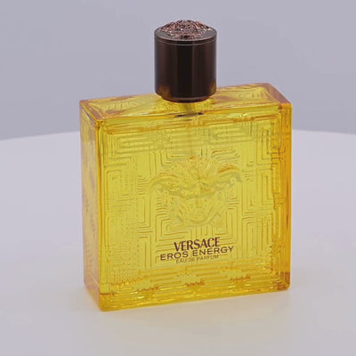 Versace Eros Energy perfume bottle rotating on a white podium