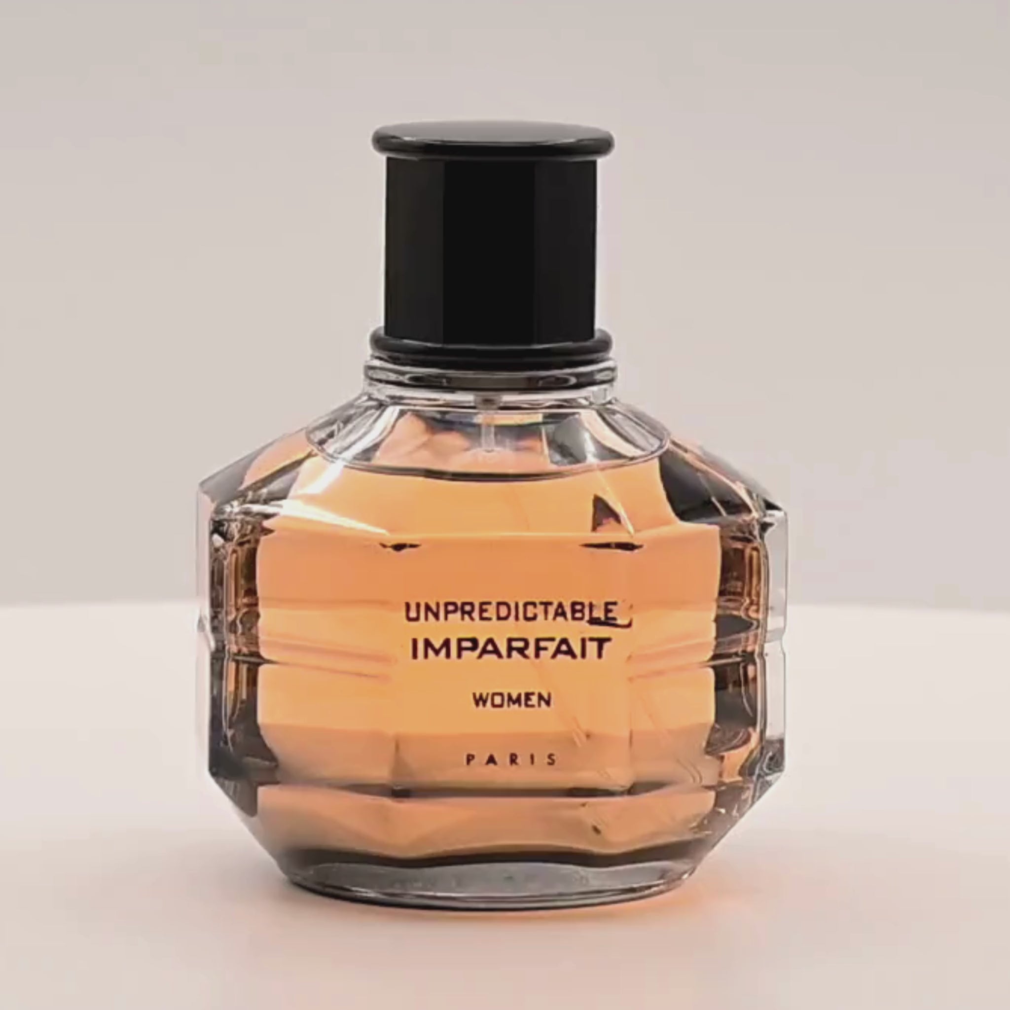 Perfume bottle labeled 'Unpredictable Imparfait' rotating on a white podium