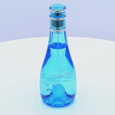 Blue perfume bottle with a spray nozzle rotating on a white podium
