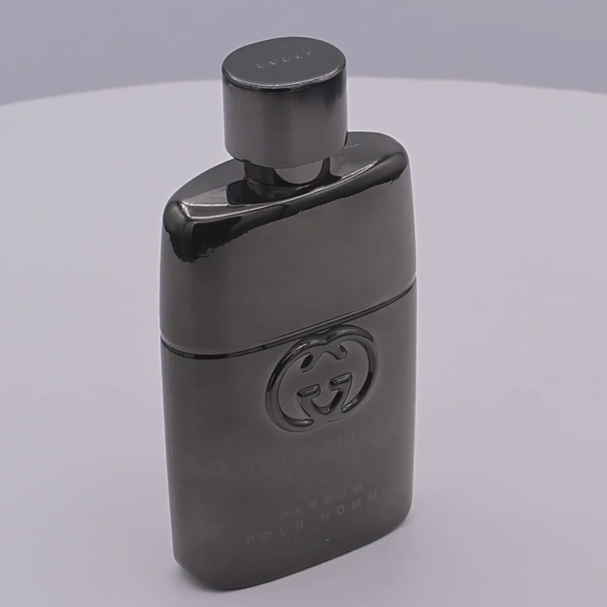 Gucci Guilty Parfum pour Homme bottle rotating on a white podium