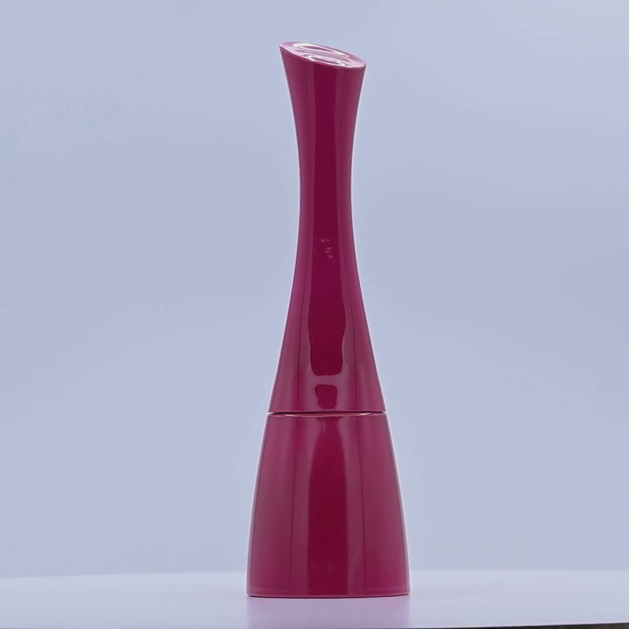 Red and pink perfume bottle rotating on a white podium