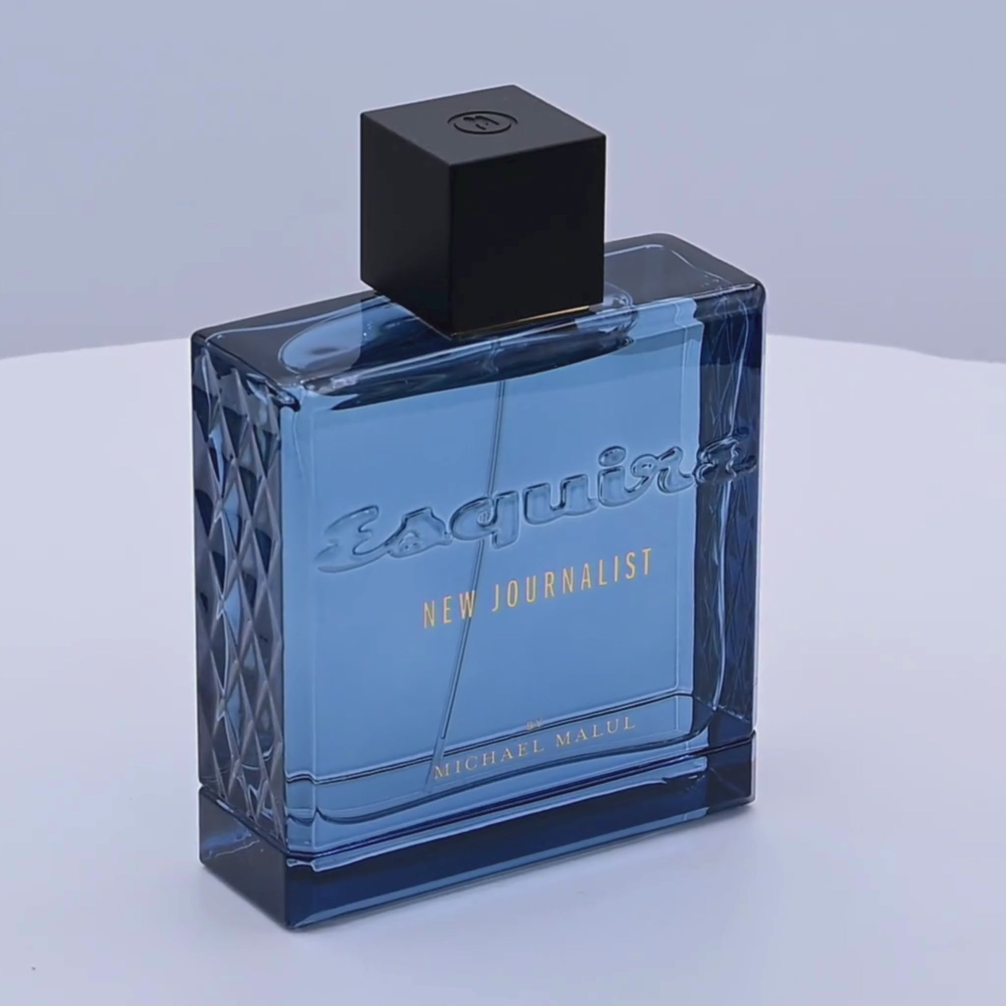 Esquire New Journalist perfume bottle rotating on a white podium