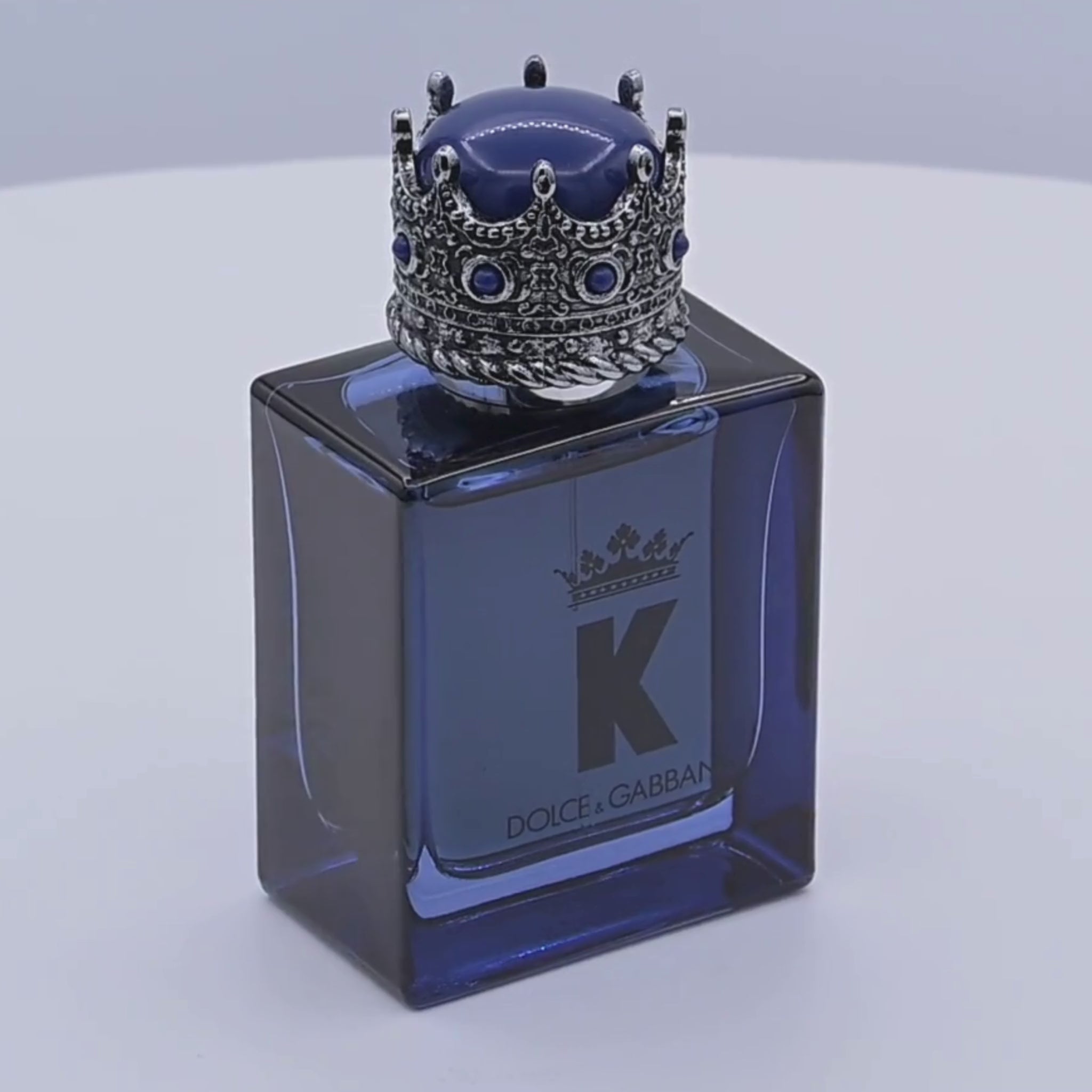 Dolce & Gabbana K perfume bottle rotating on a white podium