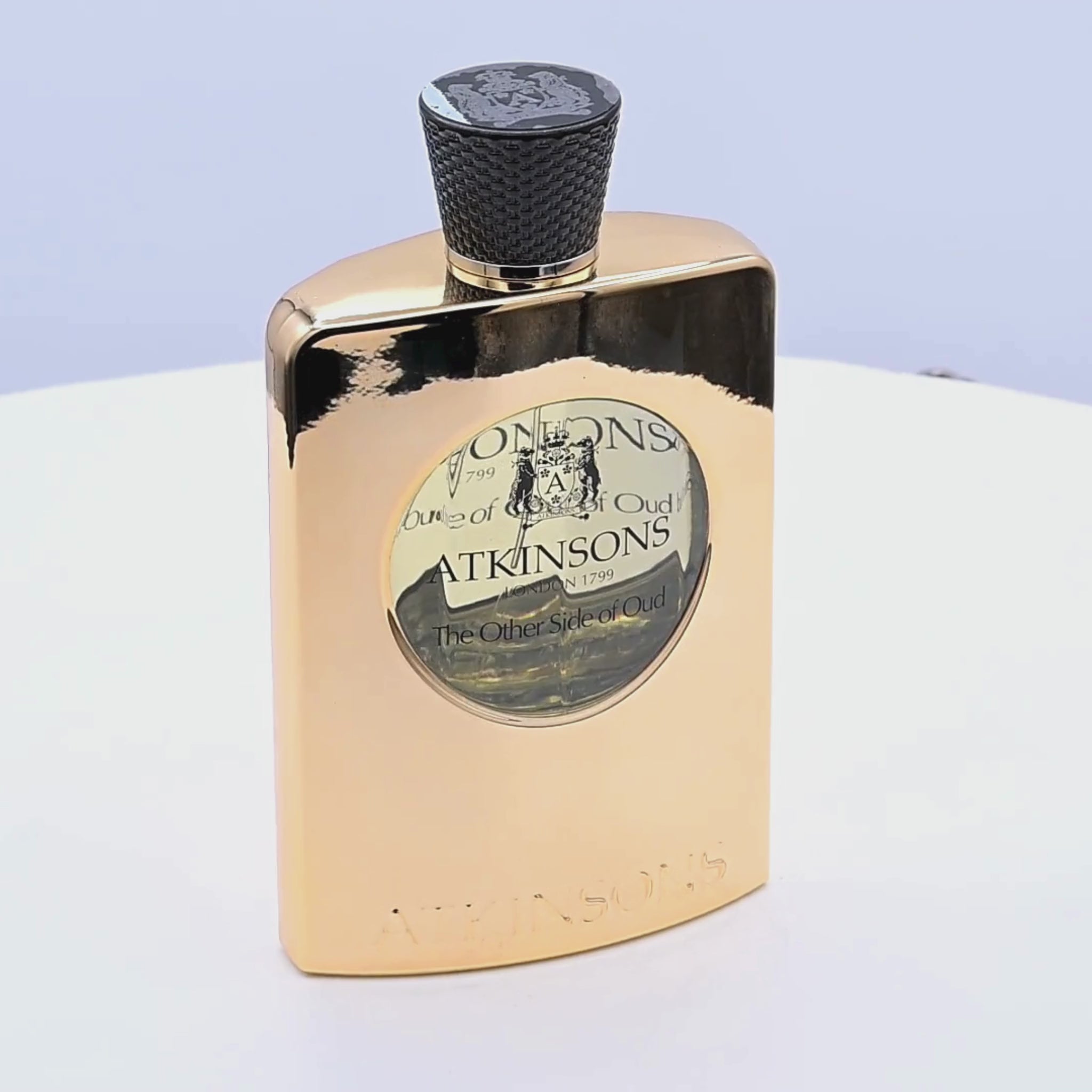 Gold Atkinsons perfume bottle rotating on a white podium