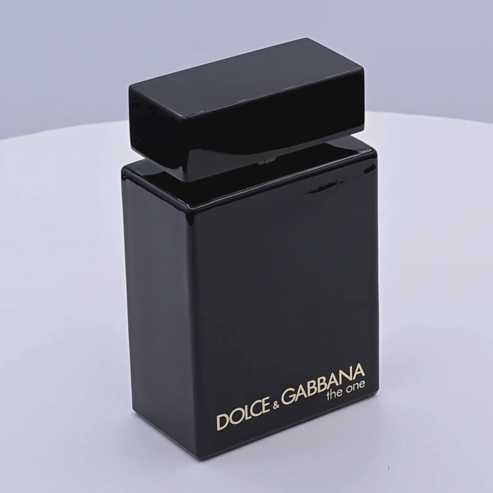 Black Dolce & Gabbana perfume bottle rotating on a white podium