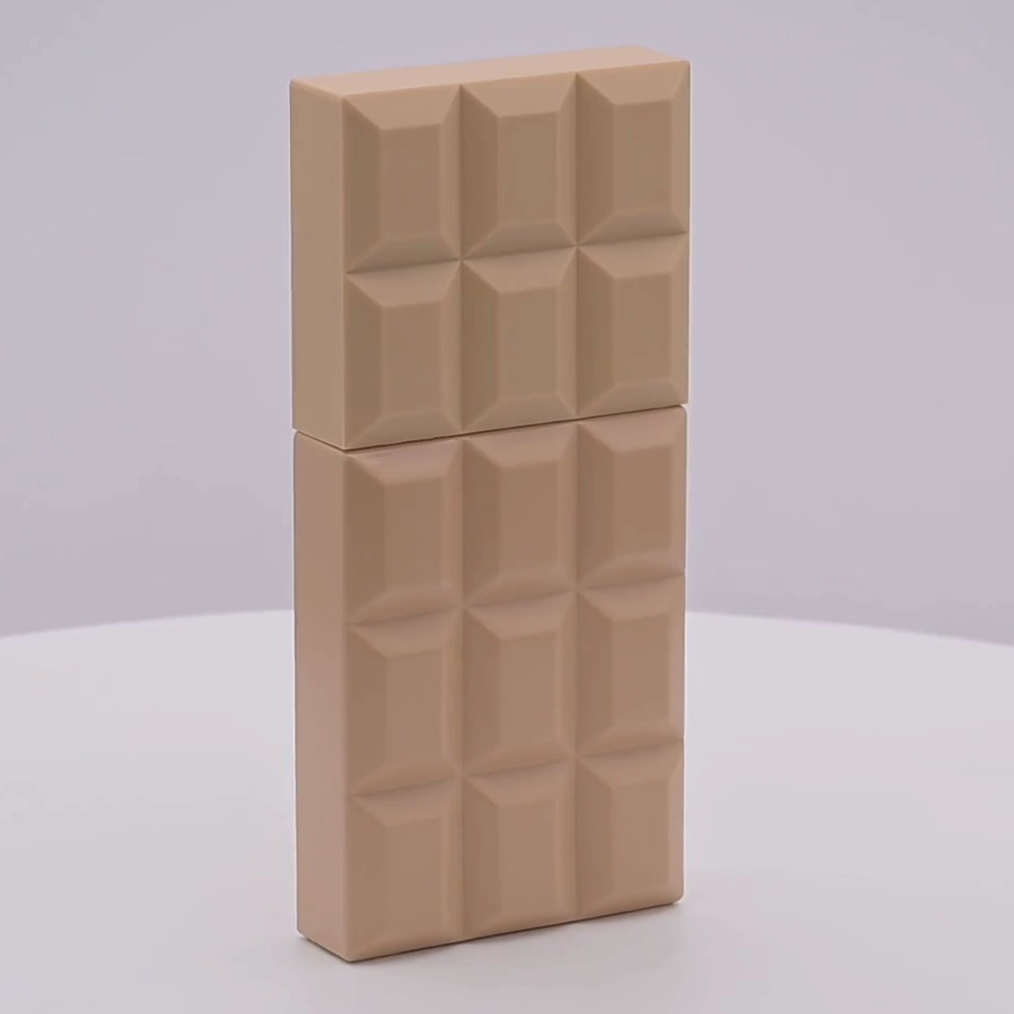 Rectangular chocolate bar shaped perfume bottle with a geometric pattern rotating on a white podium