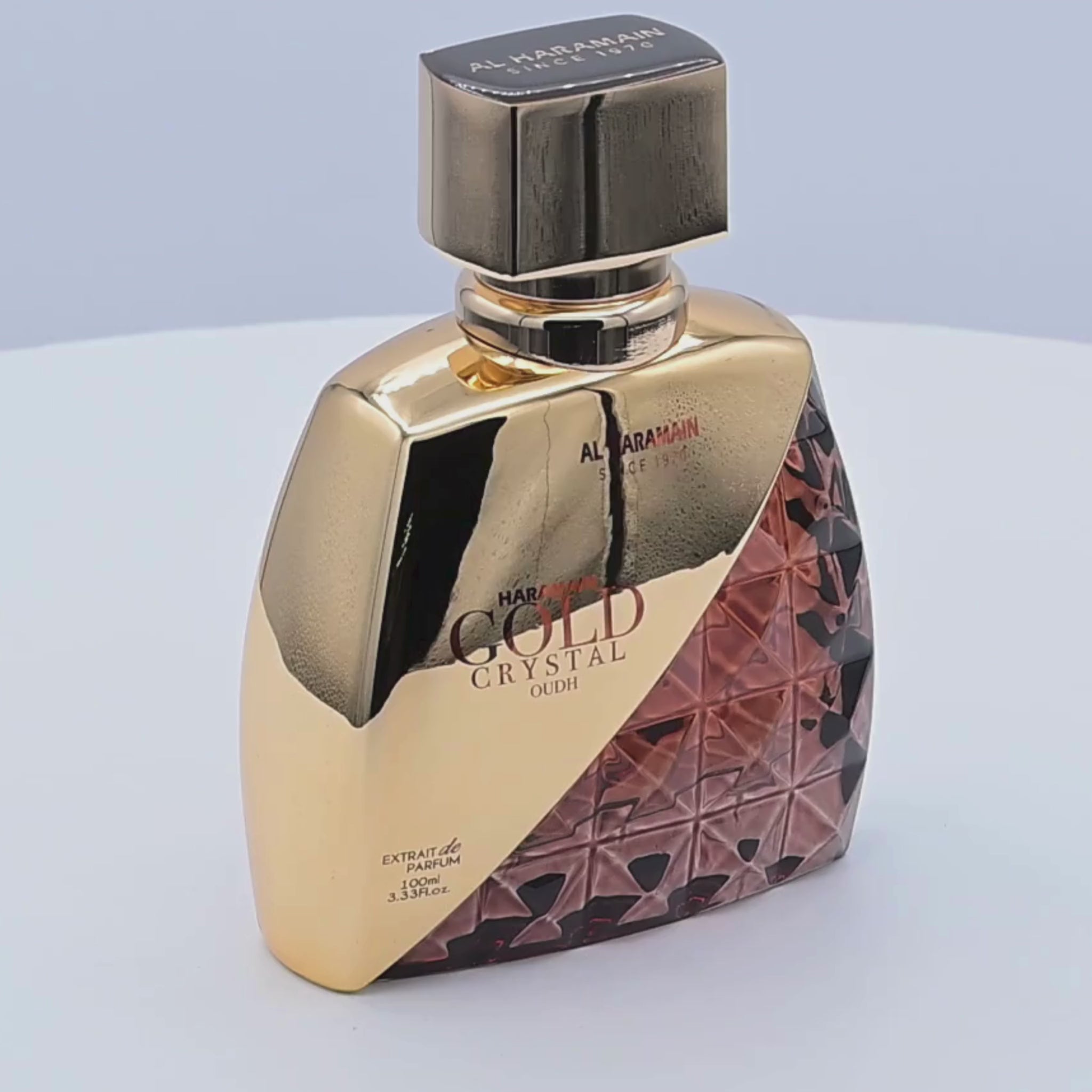Al Haramain Gold Crystal Oudh perfume bottle rotating on a white podium