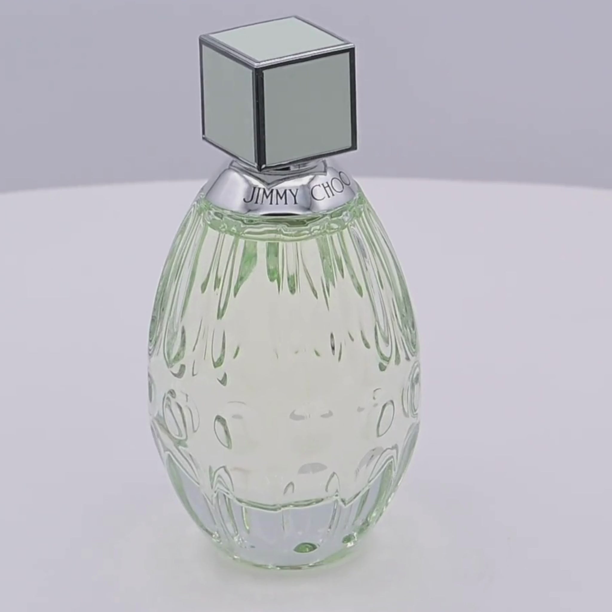 Jimmy Choo floral perfume bottle rotating on a white podium