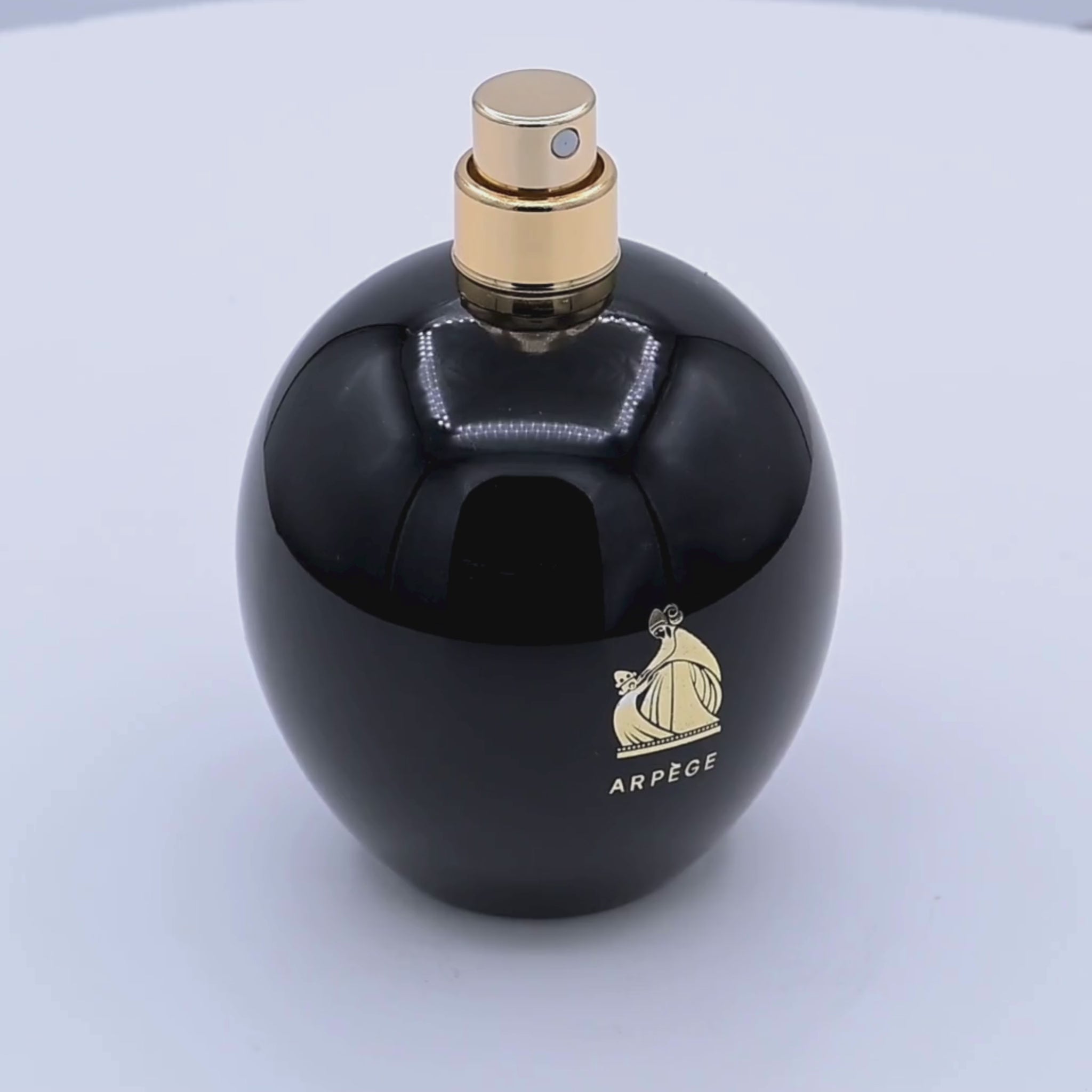 Black perfume bottle with gold cap and Arpege logo rotating on a white podium