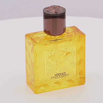Versace Eros Energy perfume bottle rotating on a white podium