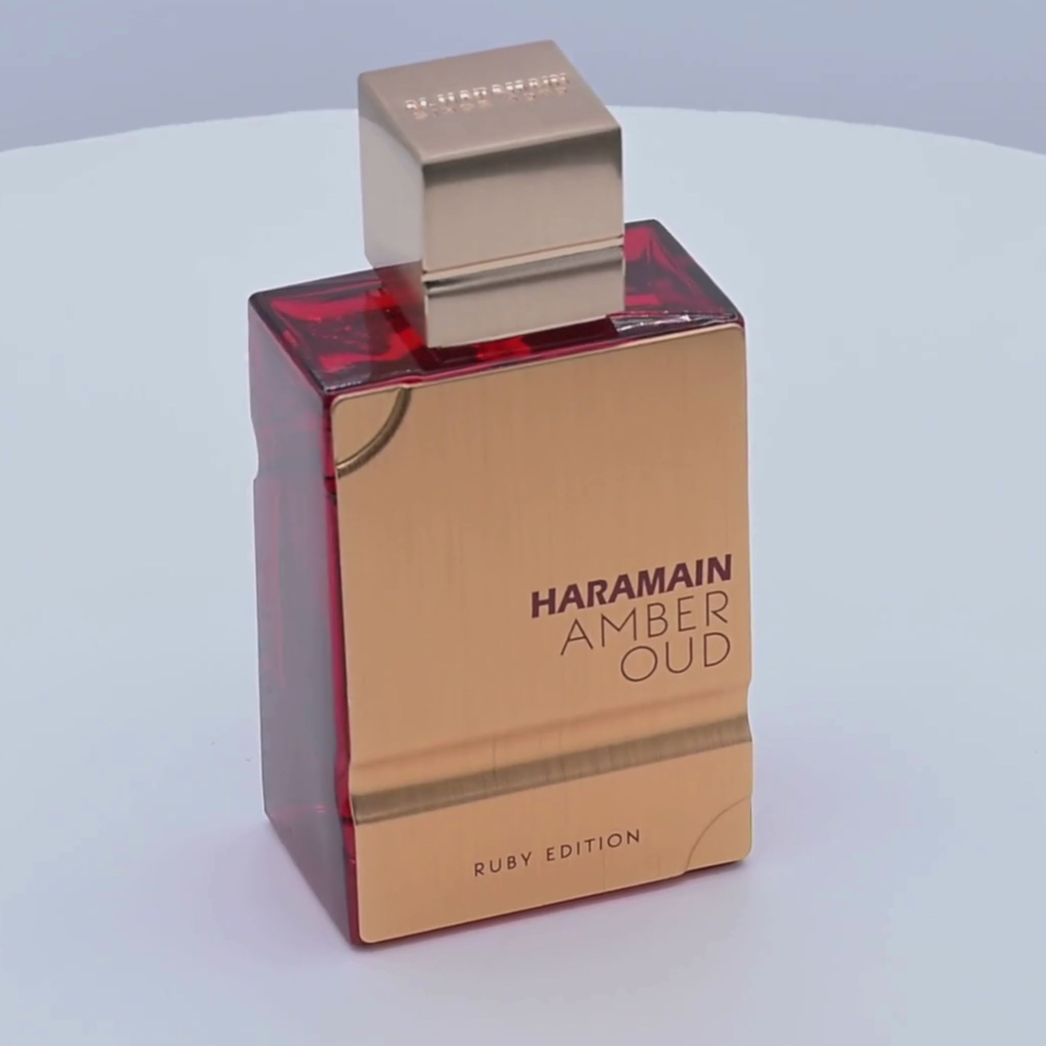 Haramain Amber Oud Ruby Edition perfume bottle rotating on a white podium