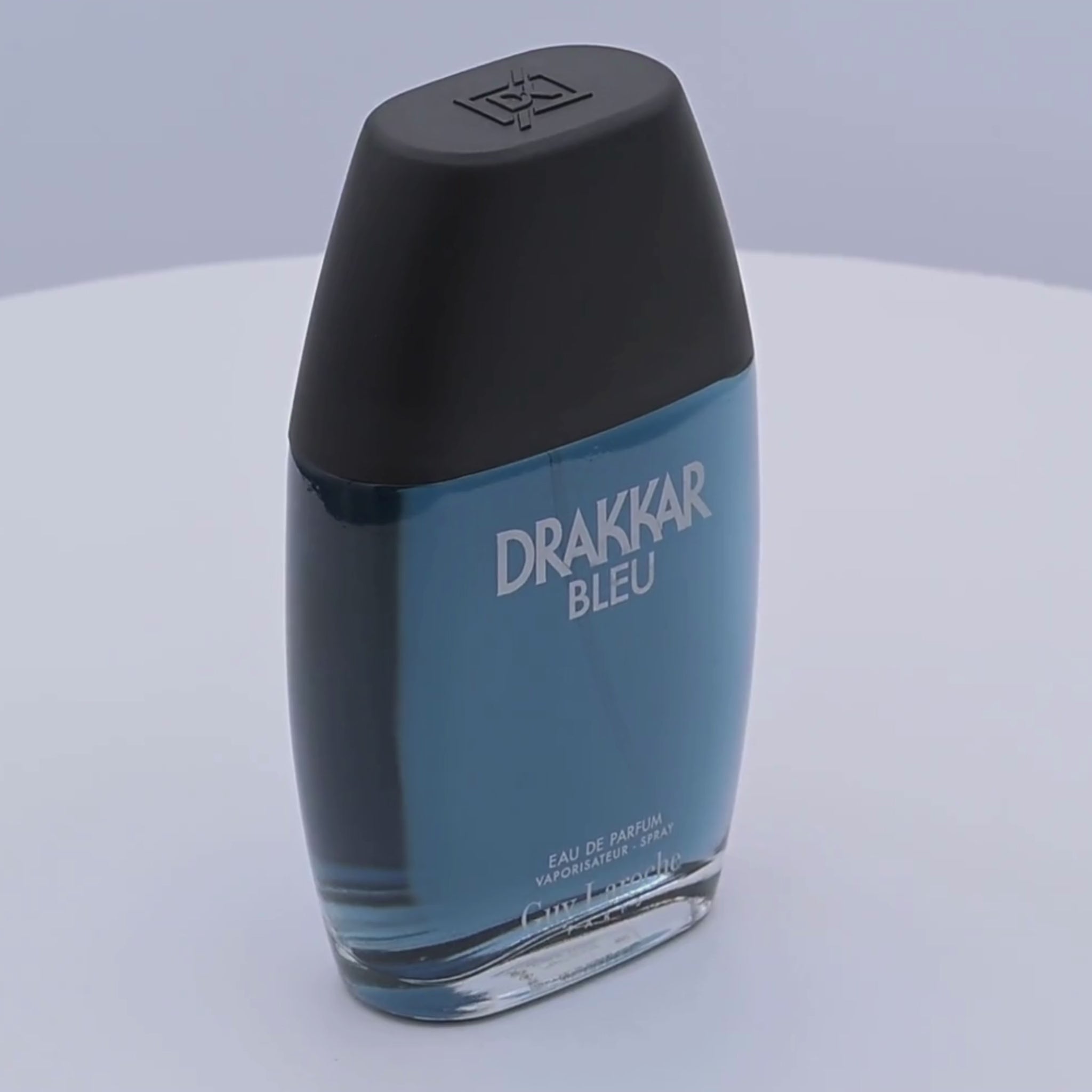 Drakkar Bleu perfume bottle rotating on a white podium