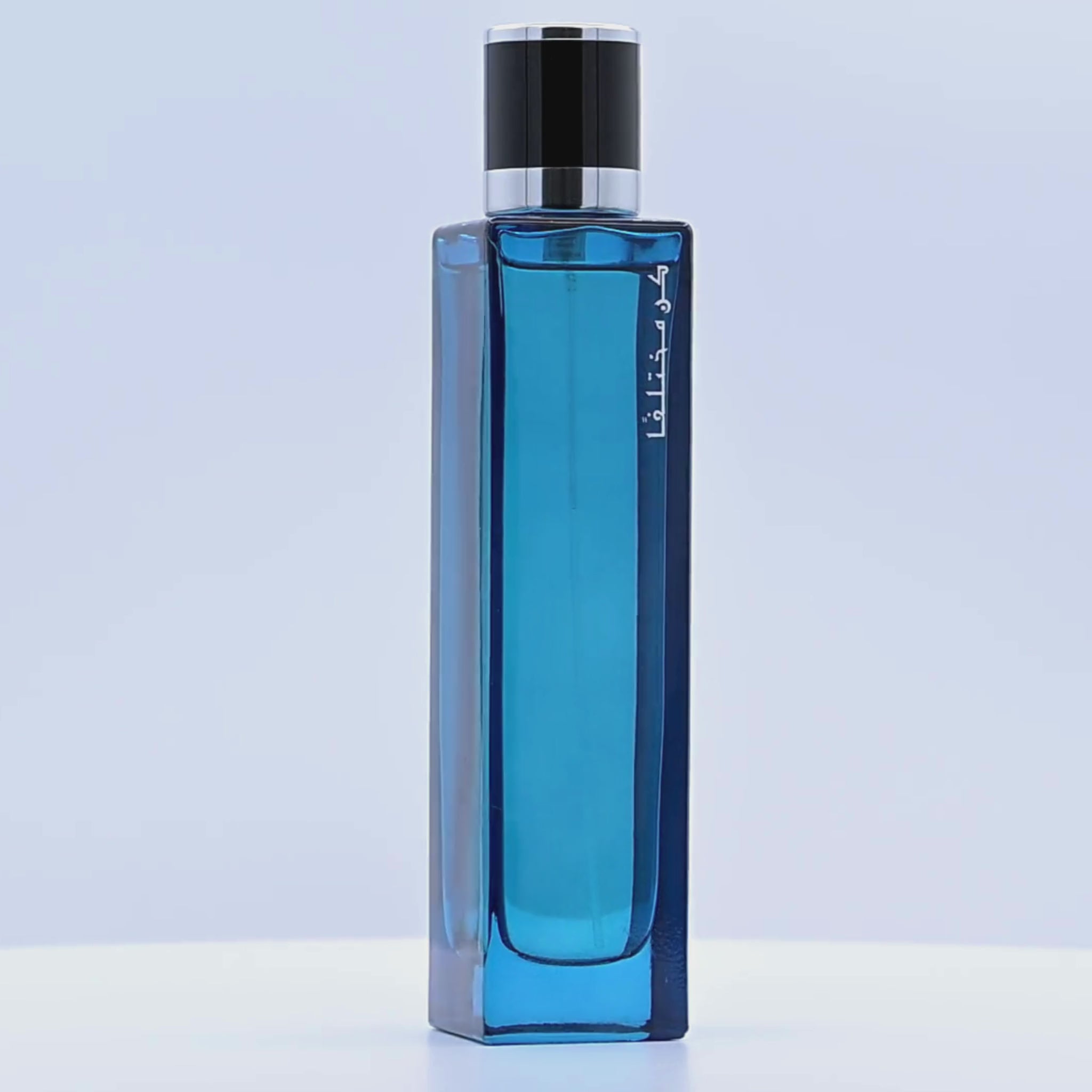 Blue perfume bottle with black cap rotating on a white podium