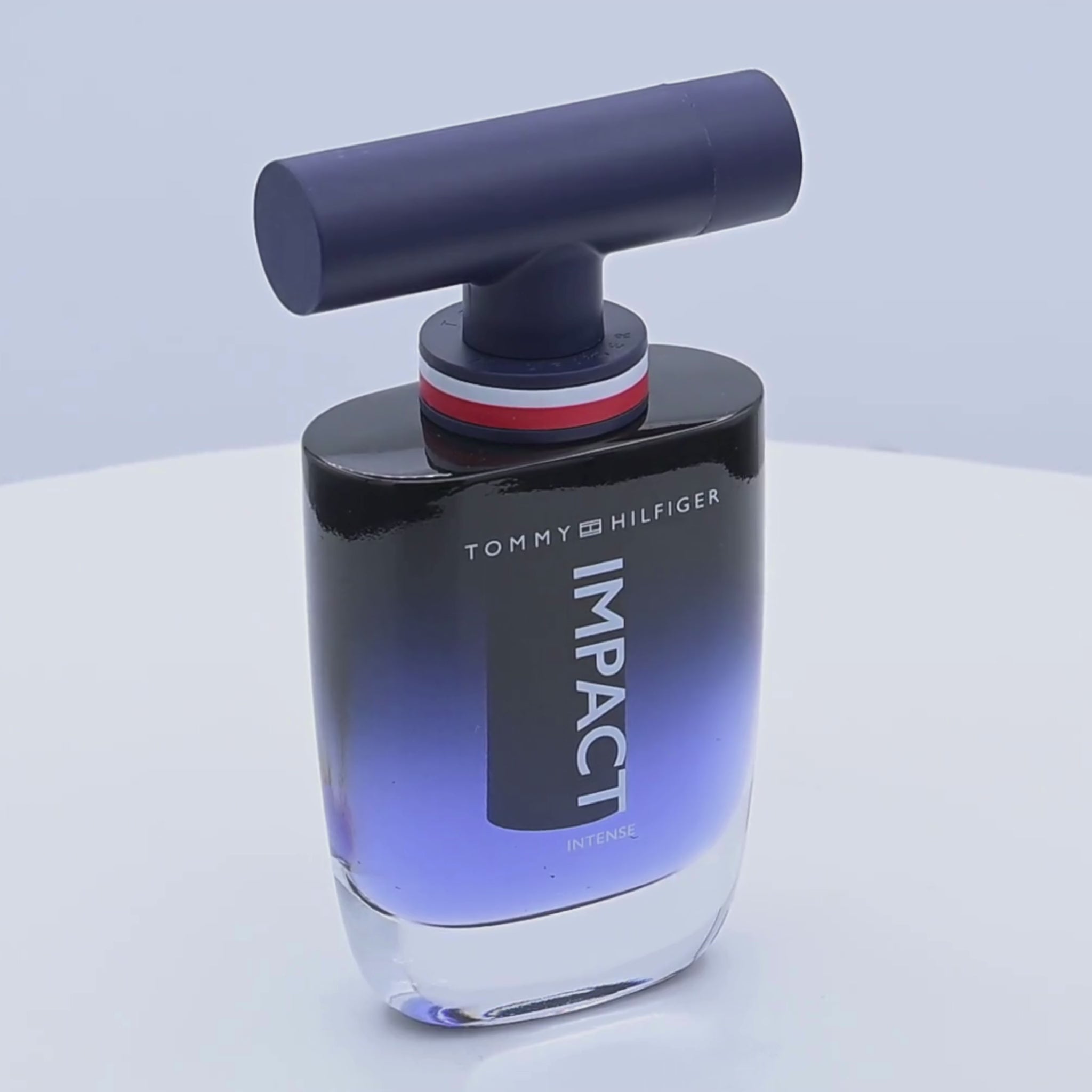 Tommy Hilfiger Impact perfume bottle rotating on a white podium