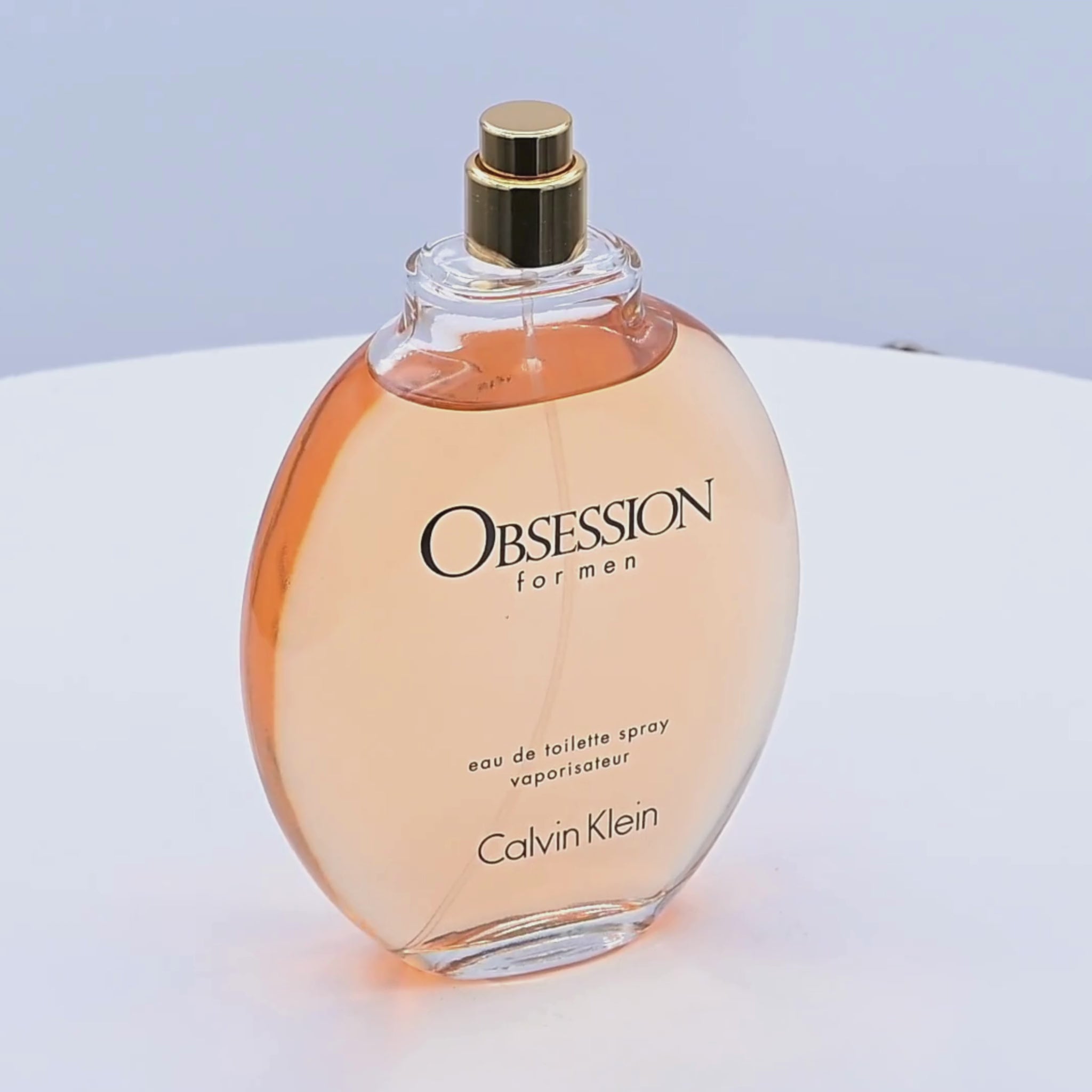 Calvin Klein Obsession for men perfume bottle rotating on a white podium