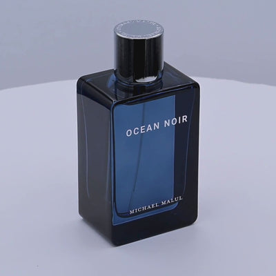Perfume bottle of 'Ocean Noir' by Michael Malul rotating on a white podium