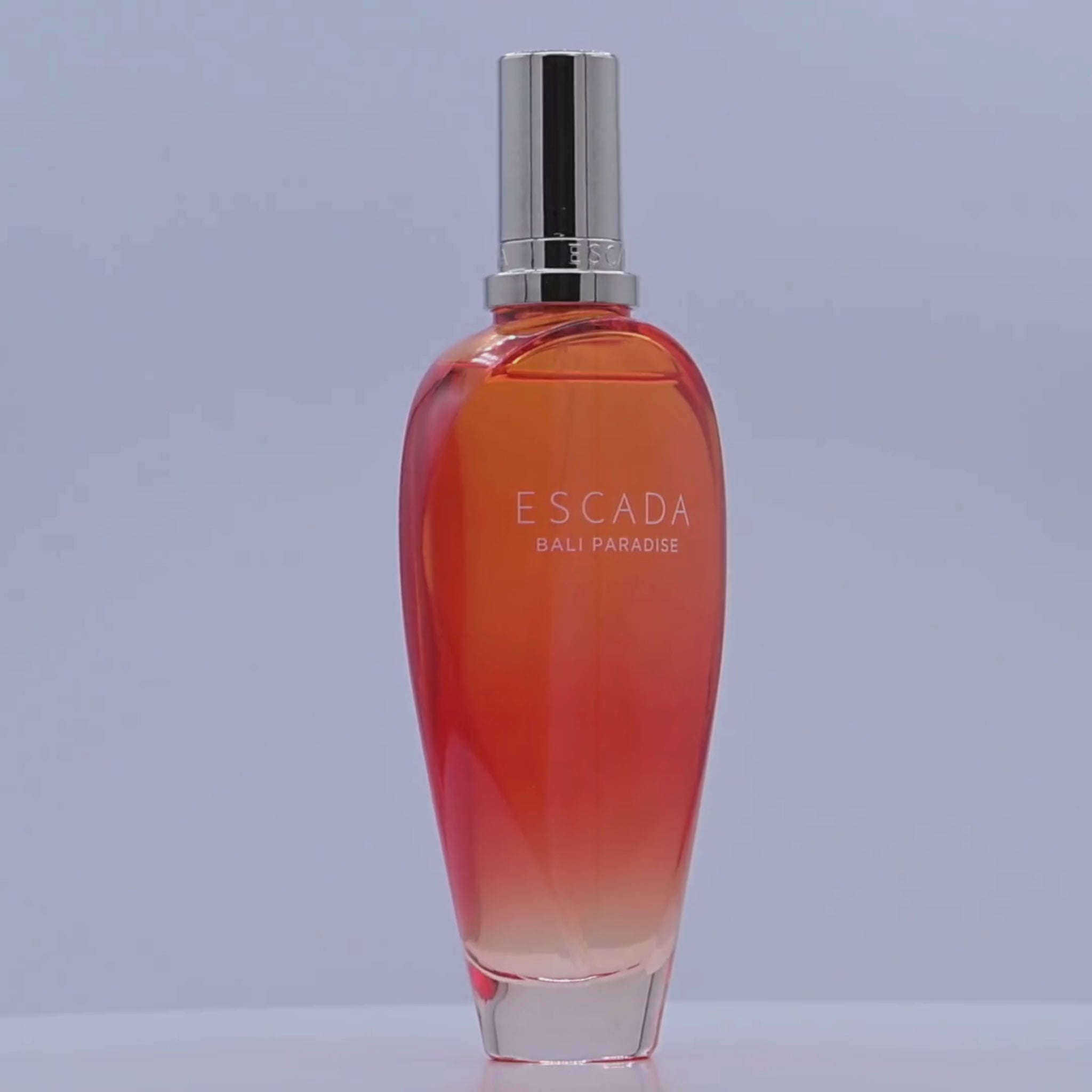 Escada Bali Paradise perfume bottle rotating on a white podium