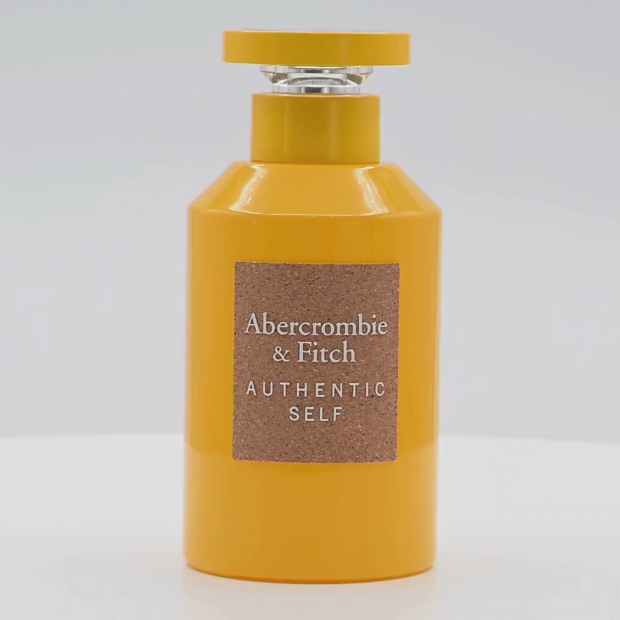 Abercrombie & Fitch Yellow perfume bottle rotating on a white podium
