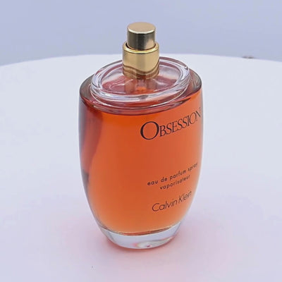 Calvin Klein Obsession perfume bottle rotating on a white podium